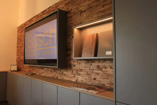 Modernes Wohnzimmer mit Steinwand, maßgefertigten Möbeln und Holzmustern für Bodenbeläge.