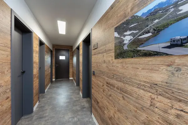 Moderner Flur mit Holzwandverkleidung, mehreren Türen und Landschaftsbild im Bürogebäude.