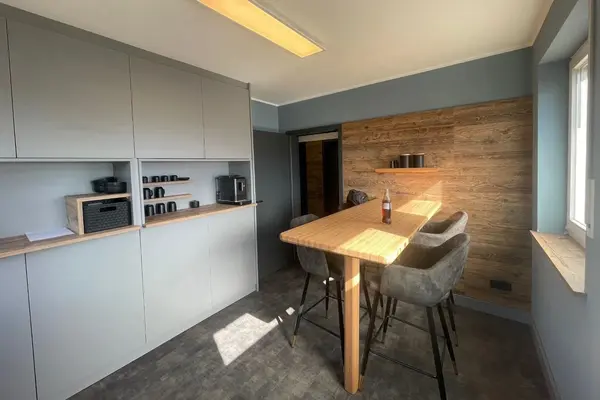 Moderne Teeküche mit Holz-Esstisch, Barhockern und Einbauschränken im Büro.